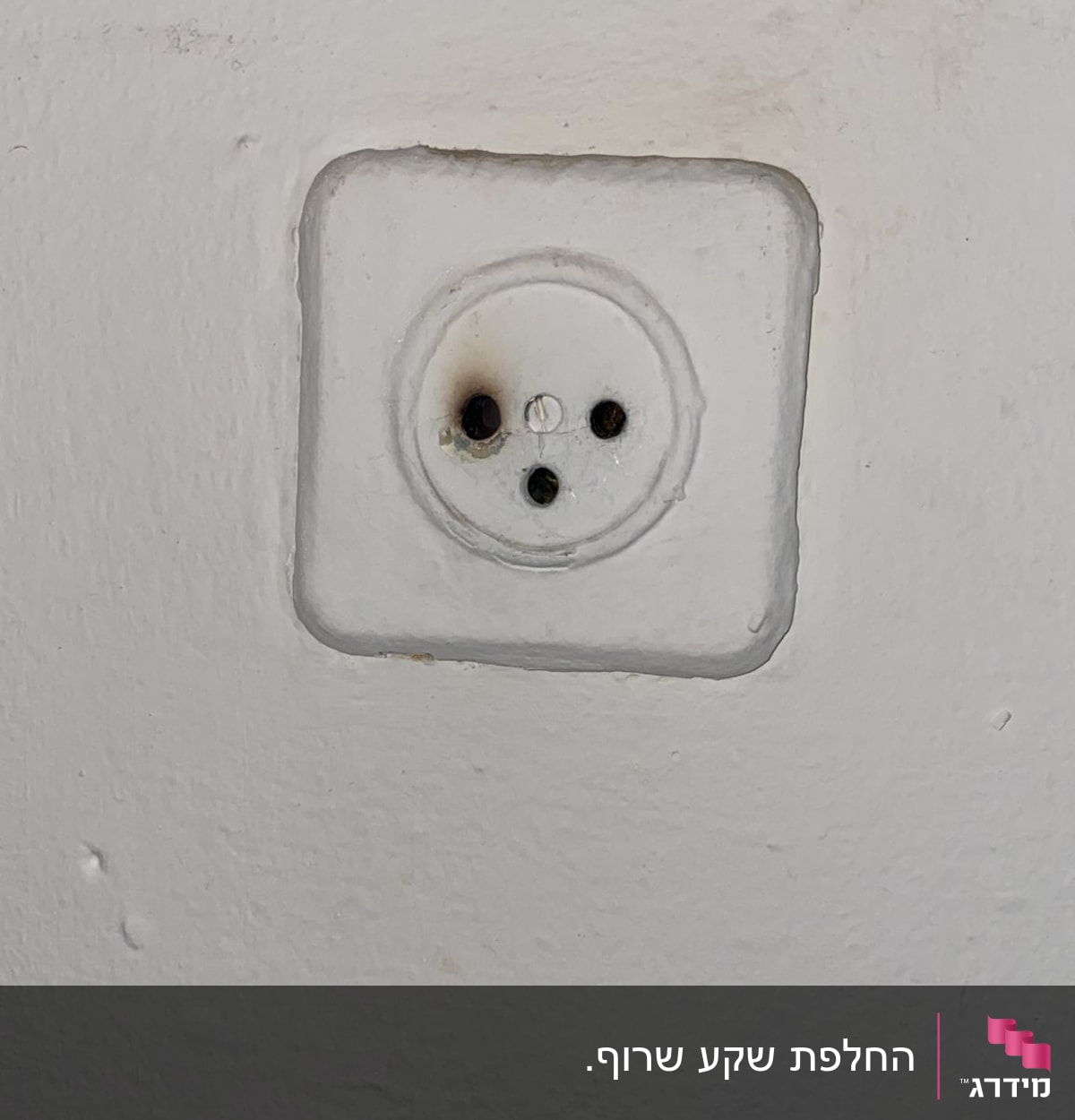 שקע חשמלי עם סימני שריפה סביב החורים